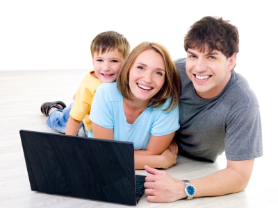 Three happy laughing people with little boy on the floor with laptop - indoors